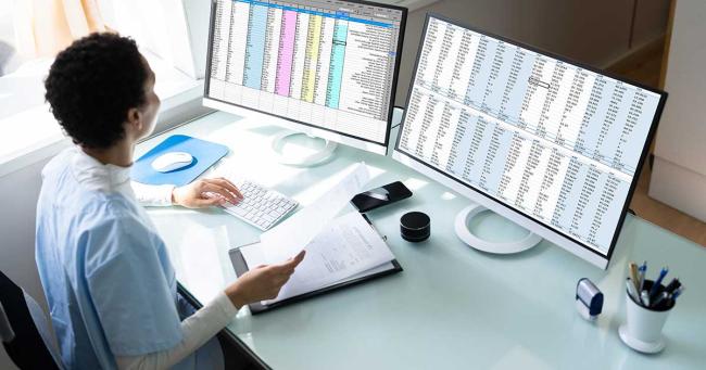 Woman seated at a desk with two computer monitors